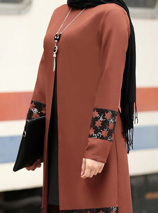 Rust-colored long tunic, intricate embroidered cuffs, black fringed scarf, clutch, and pendant necklace set.